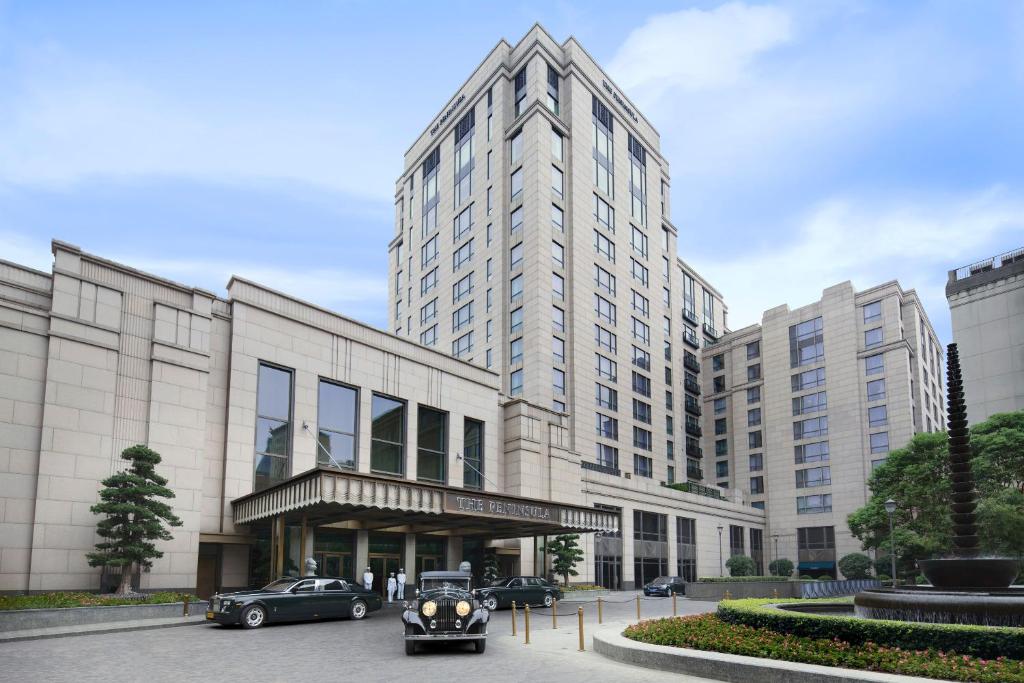 un gran edificio con coches estacionados frente a él en The Peninsula Shanghai en Shanghái