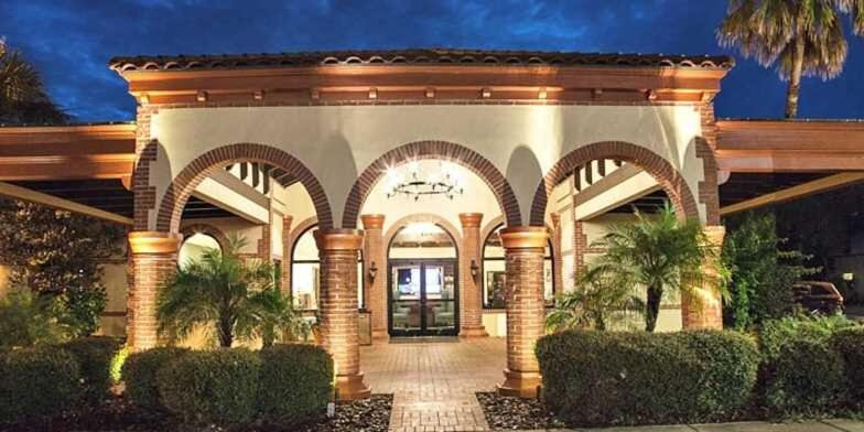 un grand bâtiment avec des arches et des arbres devant dans l'établissement The Flagler Inn - Saint Augustine, à Saint Augustine