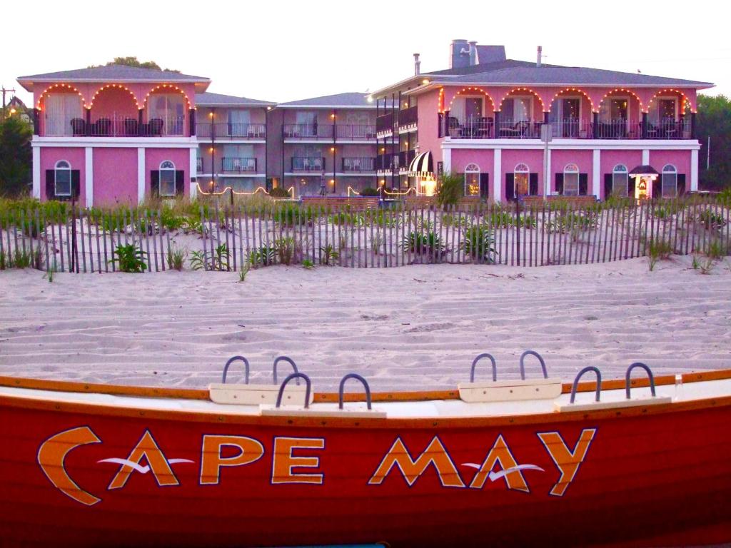 um barco sentado na praia em frente a uma casa em Periwinkle Inn em Cape May