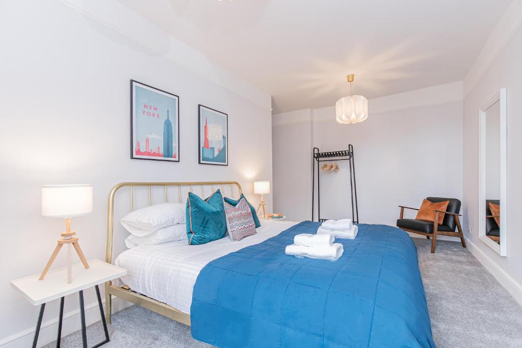 a bedroom with a blue bed with towels on it at Oxfordshire Living - The Spencer Apartment - Woodstock in Woodstock