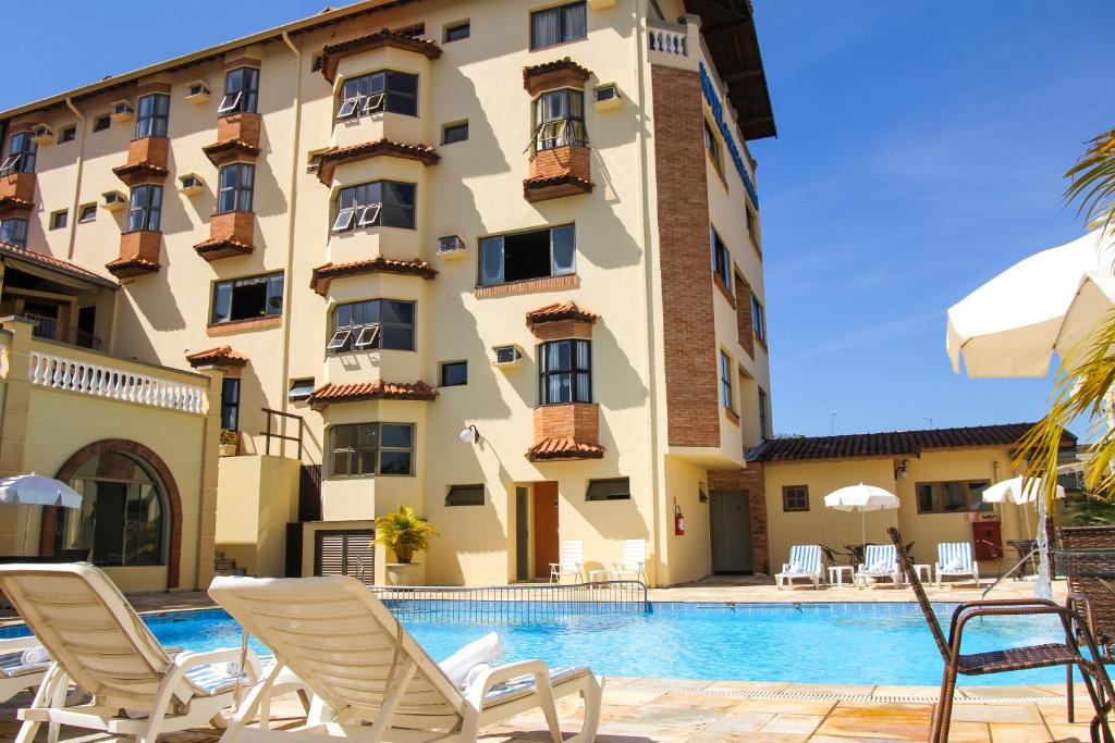 un hôtel avec une piscine en face d'un bâtiment dans l'établissement Hotel Portal das Aguas, à Águas de São Pedro