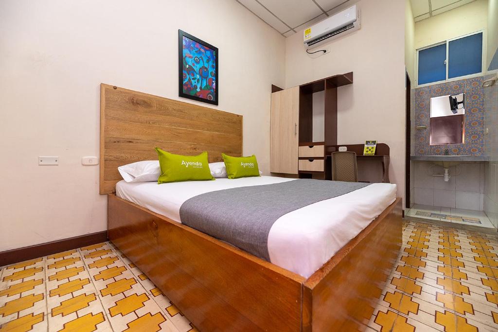 a bedroom with a large bed with green pillows at Hotel Ayenda Skall 1319 in Barranquilla