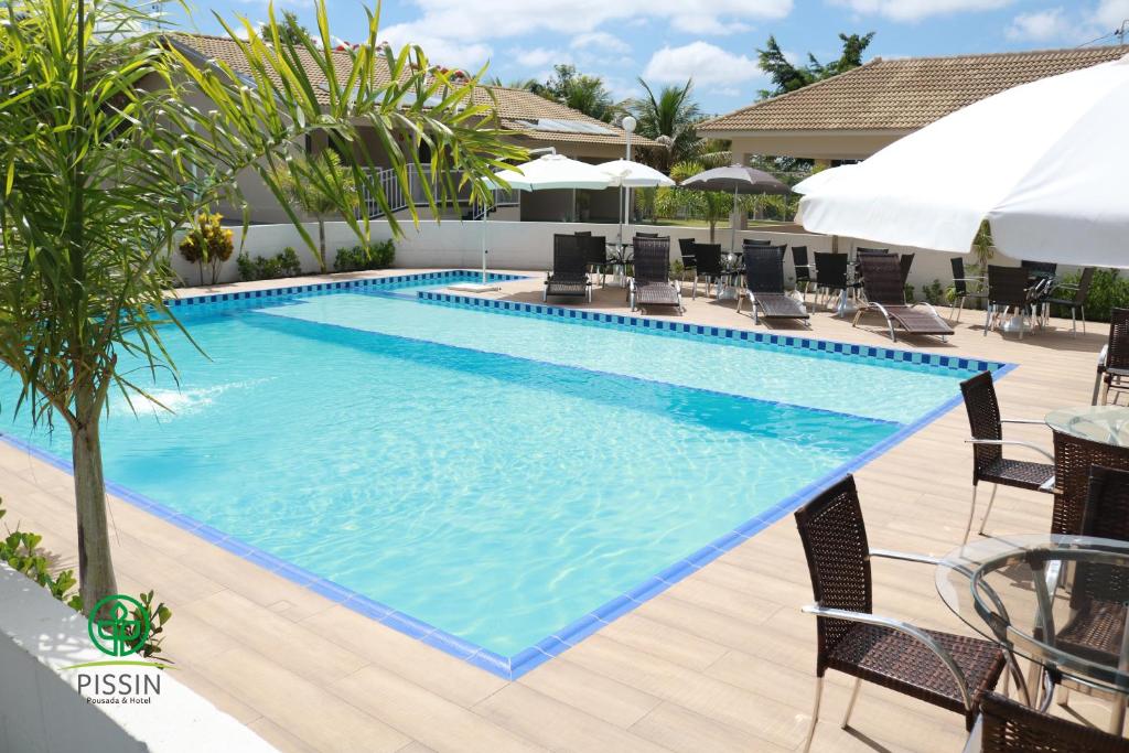uma grande piscina com cadeiras e guarda-sóis em PISSIN POUSADA E HOTEL em Marília