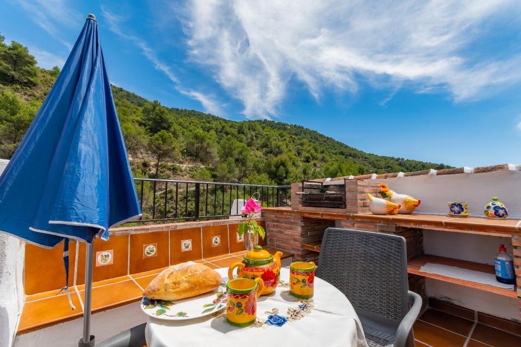 a table with a sandwich and an umbrella on a balcony at La Casita de las Mariposas in Frigiliana