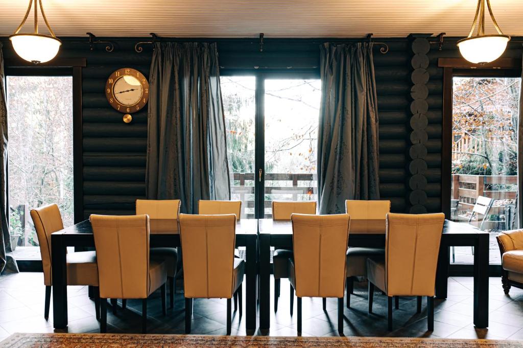 une salle à manger avec une table, des chaises et une horloge dans l'établissement Chalet MelodiyaGir, à Pilipets