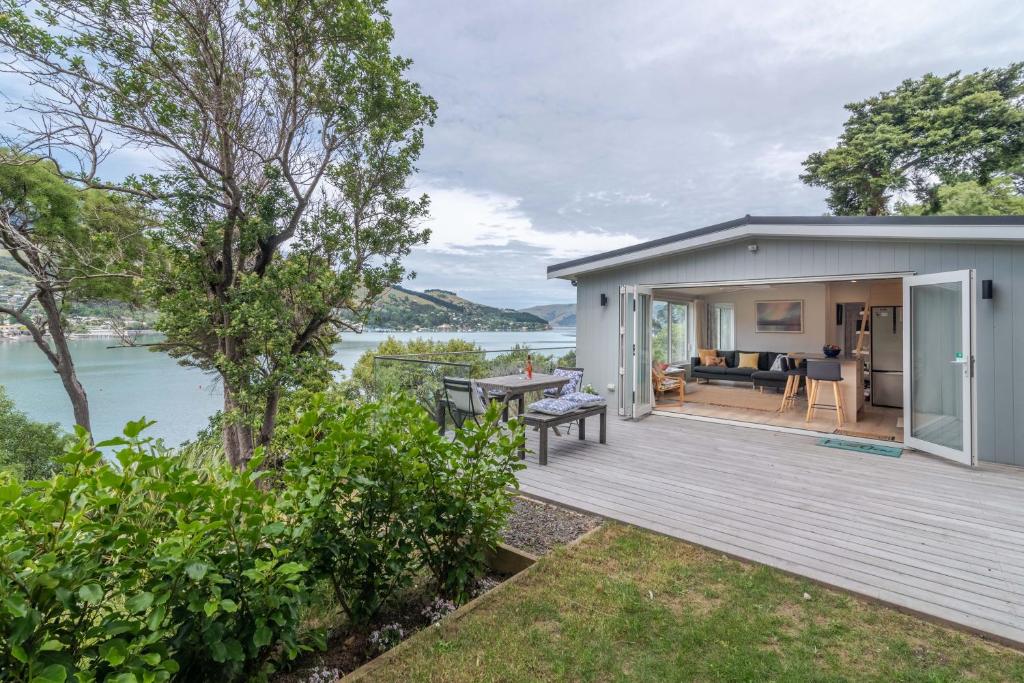 ein Haus mit einer Terrasse neben einem Wasserkörper in der Unterkunft Otahuahua - Akaroa Holiday Home in Takamatua Bay