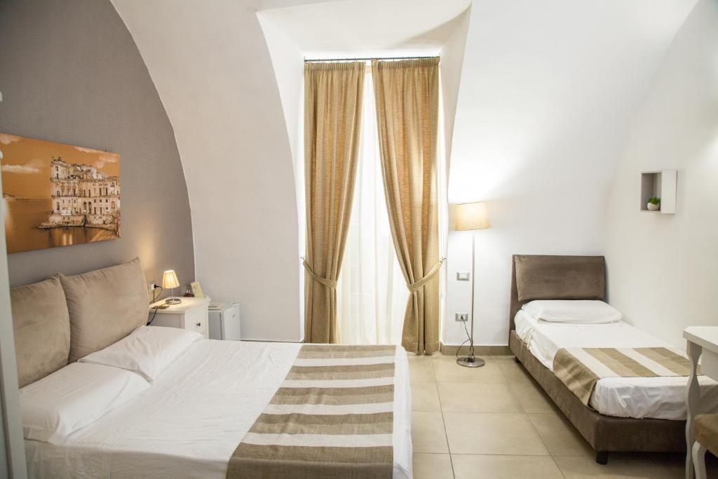 um quarto de hotel com duas camas e uma janela em Chiaia Suites em Nápoles