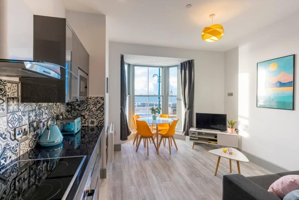a kitchen and living room with a table and chairs at New central seafront apartment- stunning sea views in Aberystwyth