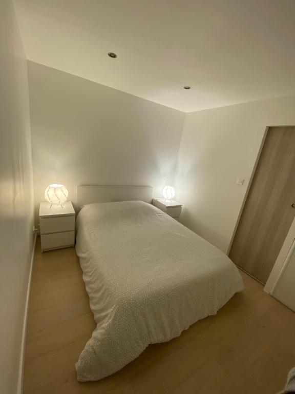 ein weißes Schlafzimmer mit einem Bett und zwei Lampen in der Unterkunft Appartement les Falaises in Cap d'Agde