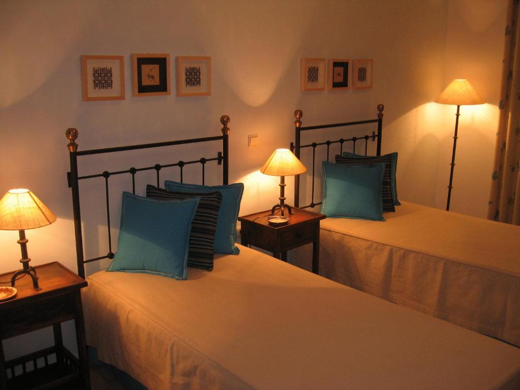 two beds in a bedroom with two lamps on tables at Casa Fatana in São João dos Caldeireiros