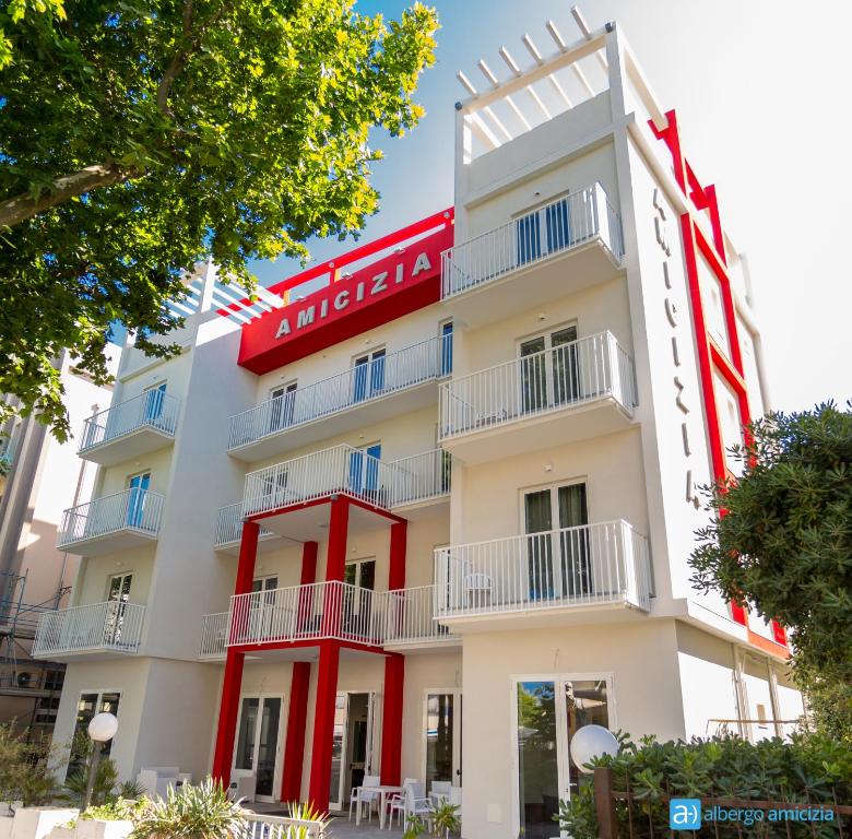 an apartment building with a red and white facade at Hotel Amicizia in Rimini