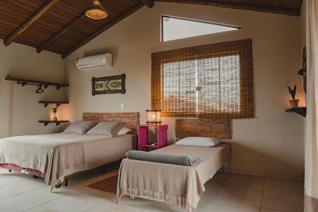 a bedroom with two beds and a window at Pousada Canto do Rosa in Praia do Rosa