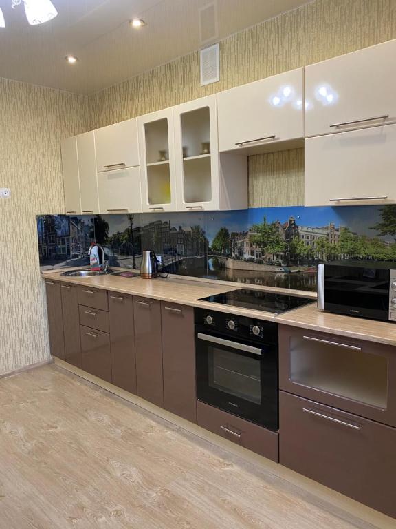 a kitchen with white cabinets and black appliances at Apartments on Aviatorov 10 in Abakan