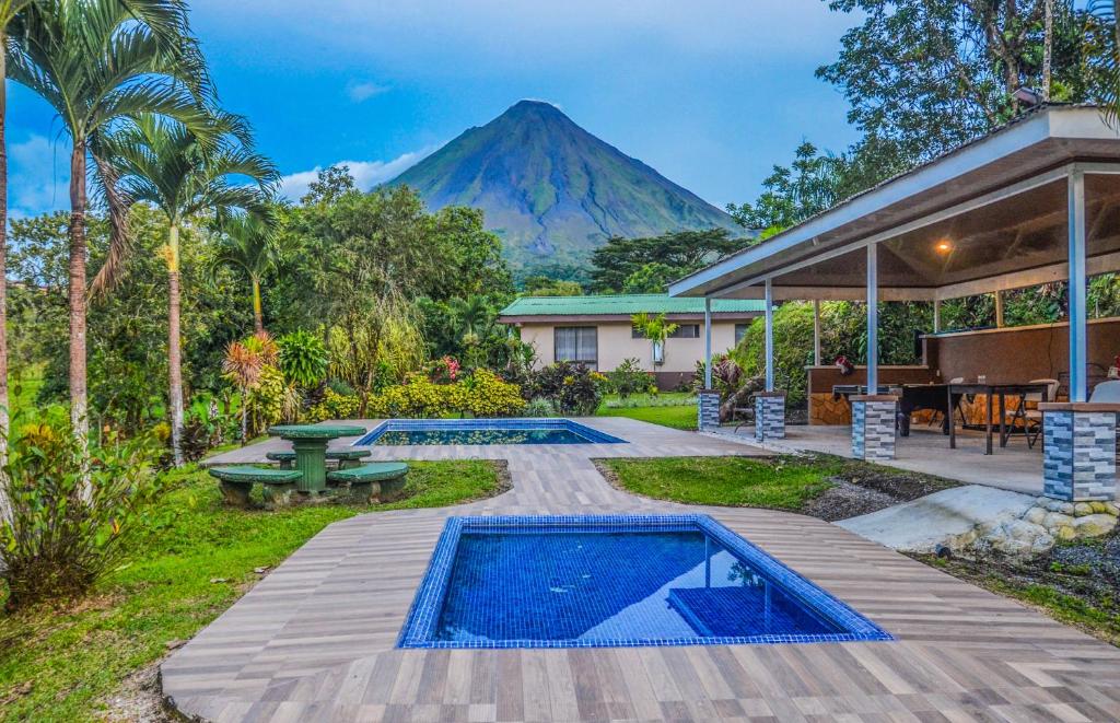 a house with a pool and a mountain in the background at Lumbres Arenal in Fortuna