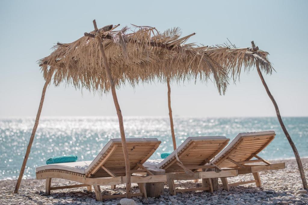 two chairs and an umbrella on a beach at Althea Beachside Apartments in Potokáki