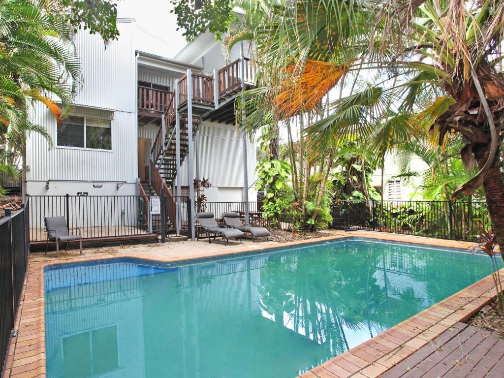 a swimming pool in front of a house with palm trees at Mayfield 23 in Alexandra Headland