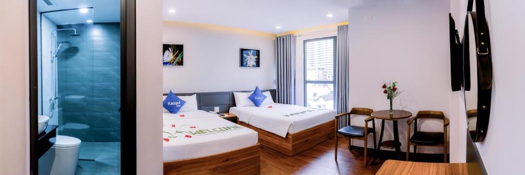 um quarto com duas camas e uma mesa e uma janela em KADUPUL HOTEL em Quy Nhon