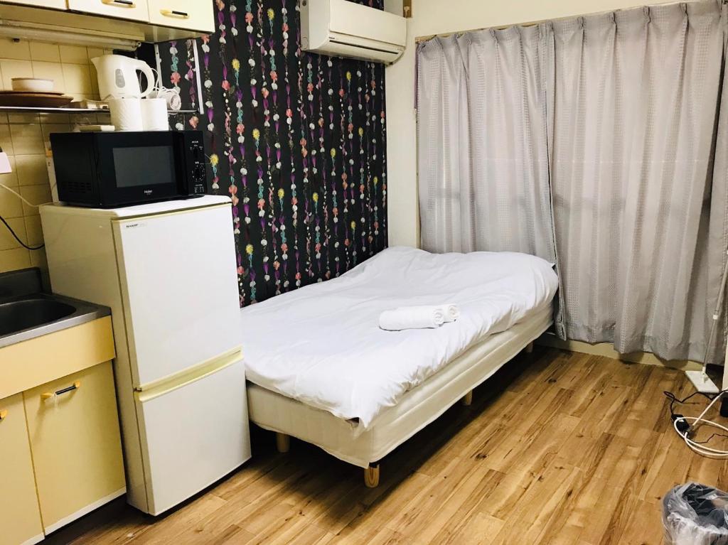 大阪市にあるEX Tenjinnomori Apartment 104の窓のある小さな部屋にある小さなベッド