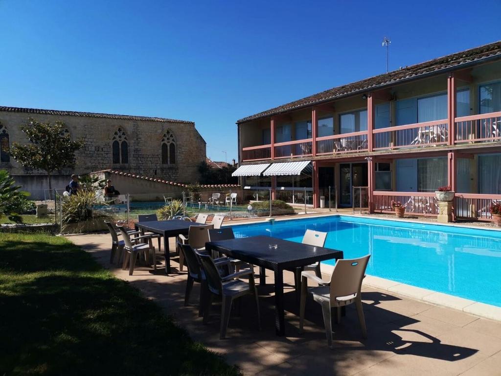 a hotel with tables and chairs next to a swimming pool at Le Logis des Cordeliers in Condom