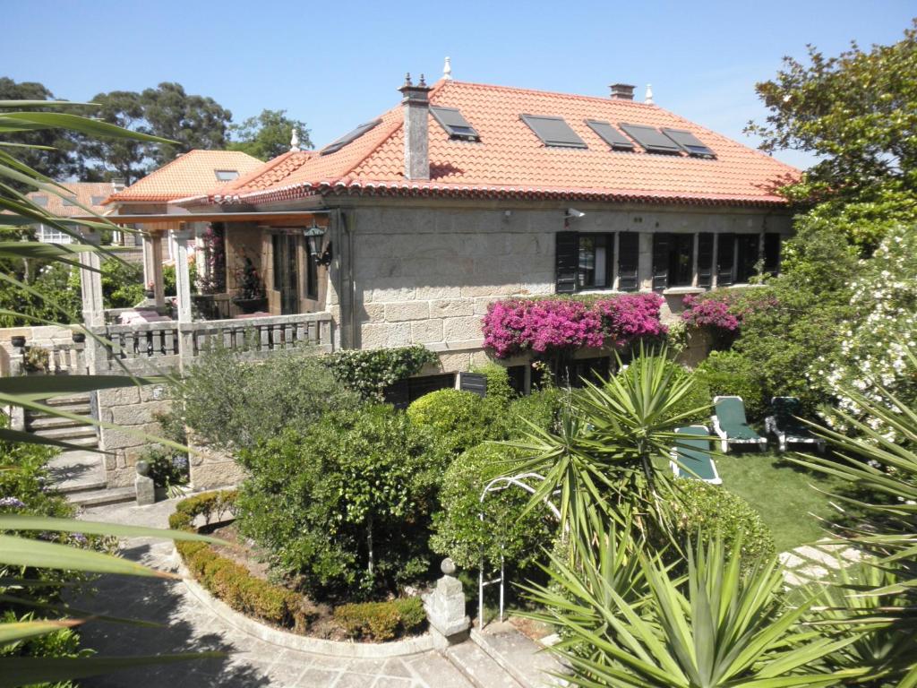 una casa con techo rojo y algunas plantas en Hotel Playa Samil Vigo, en Vigo