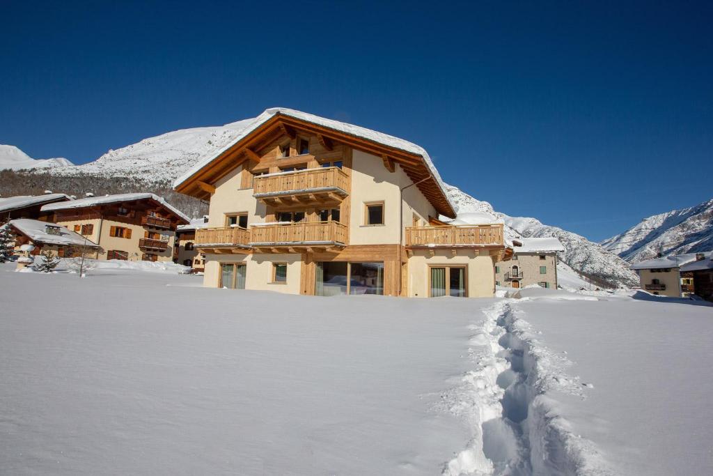une maison dans la neige avec une cour recouverte de neige dans l'établissement Chalet Cuna Bela, à Livigno