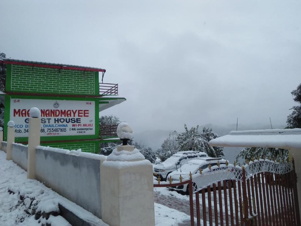 un edificio con un cartel en la nieve en Maa Anand Mayee Guest House, en Panuānaula