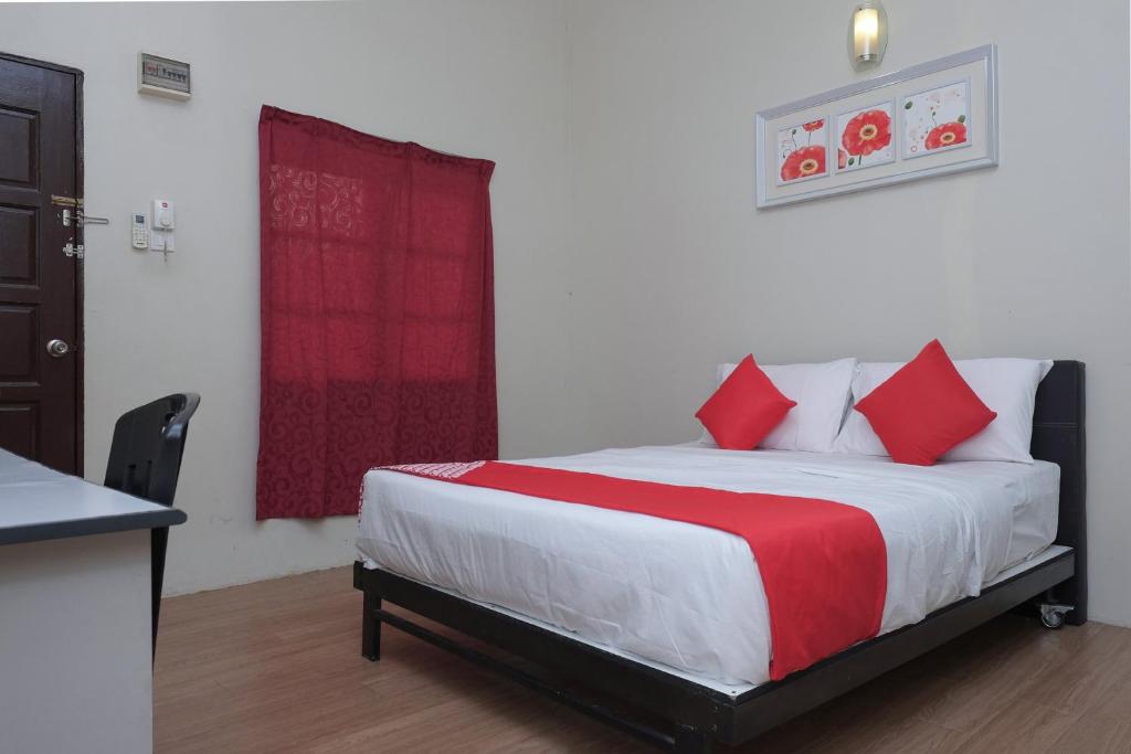 1 dormitorio con 1 cama con almohadas rojas en OYO 90080 Kay Inn Kerteh, en Kertih