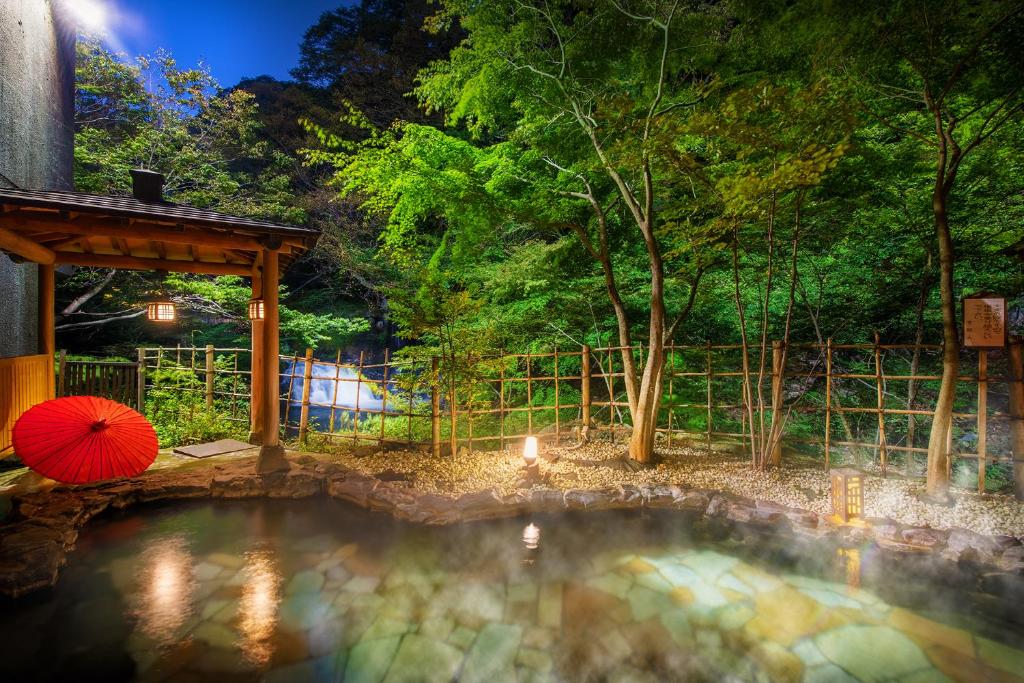 una piscina de agua con una sombrilla en un patio en Harataki en Aizuwakamatsu