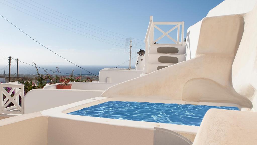 un toboggan sur le côté d'un bâtiment avec une piscine d'eau dans l'établissement Oia, Finikia Cave House, à Oia