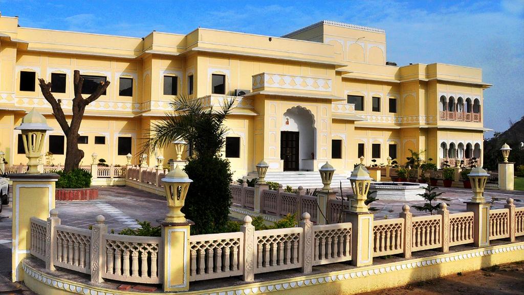 a large yellow building with a white fence at Hotel Raj Bagh Palace in Jaipur