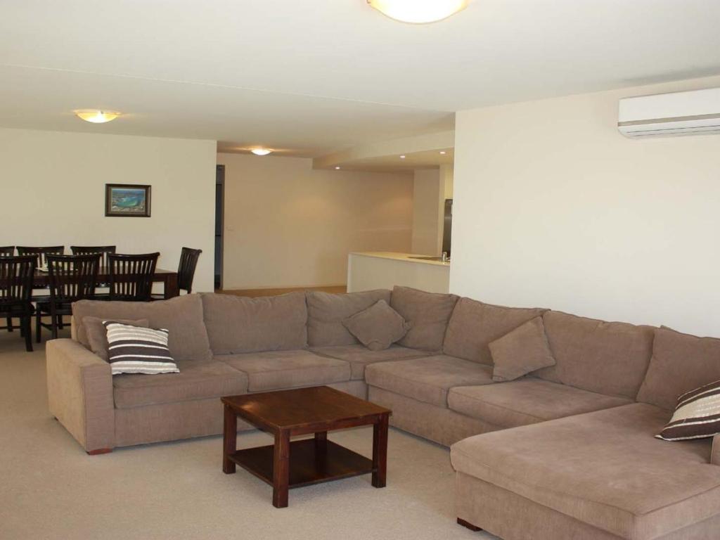a living room with a couch and a table at The Reef 103 Lakeside in Forster