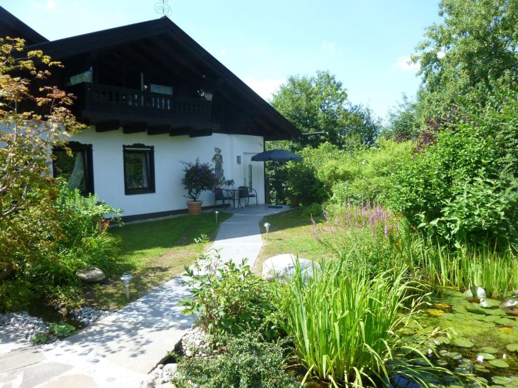 a garden with a white house with an umbrella at Ferienappartement in der Wolfsgrube-Rambichler in Chieming