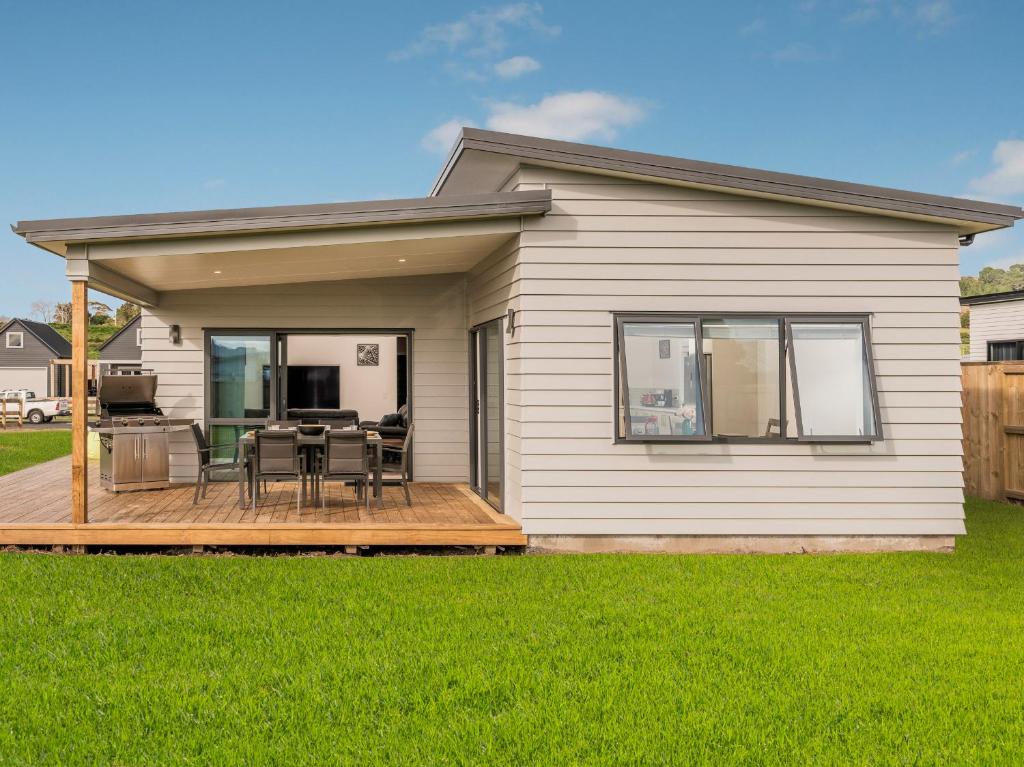 a house with a deck with a table and chairs at Seabliss - Cooks Beach Holiday Home in Cooks Beach