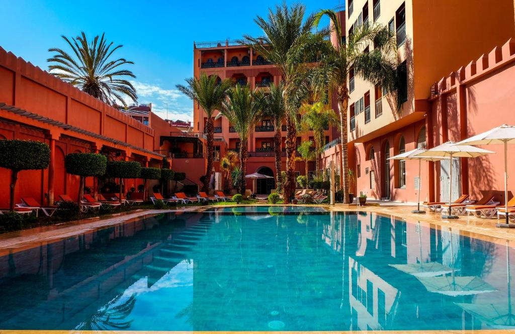 a swimming pool in a resort with palm trees and buildings at Diwane Hotel & Spa Marrakech in Marrakech