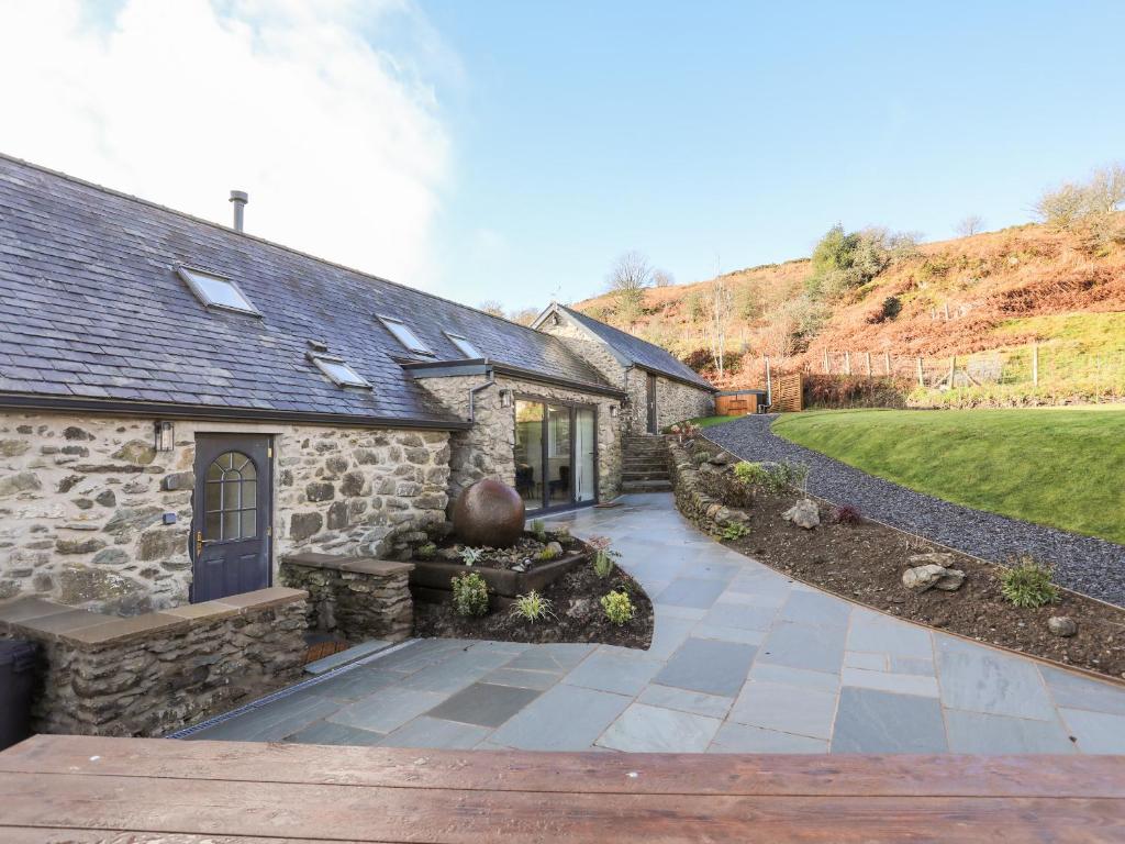 a stone house with a walkway next to a yard at Drovers Barn in Corwen