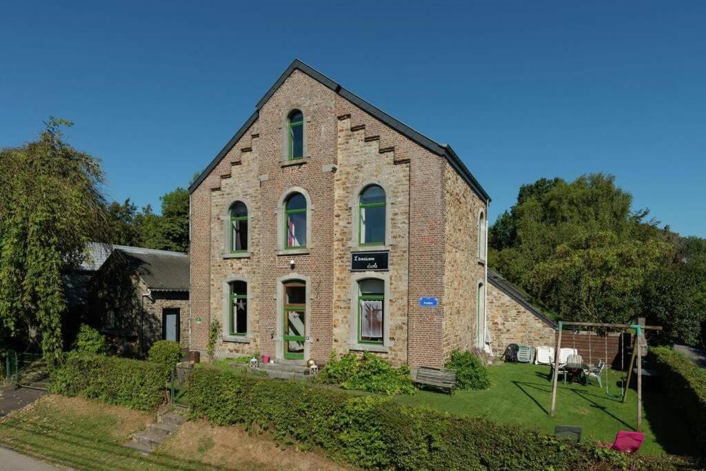 un antiguo edificio de ladrillo con puertas y ventanas verdes en L'ancienne école d'Erpigny, en Érezée
