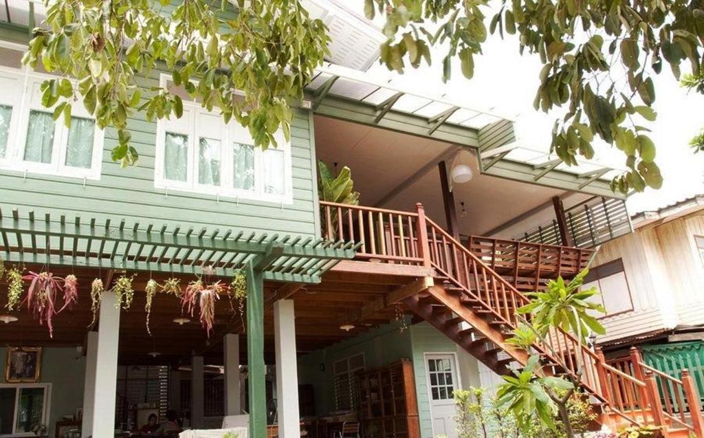 una casa verde con una terrazza in legno e scale di Ban Boonchu a Phra Nakhon Si Ayutthaya