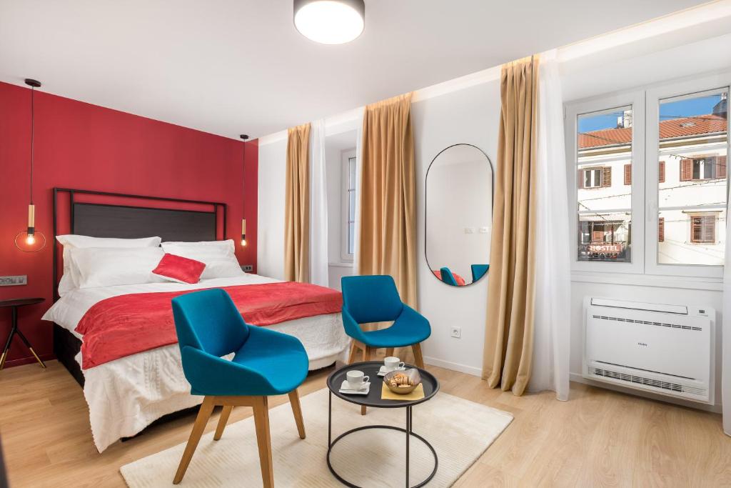 a bedroom with two blue chairs and a bed at Sweet Nest Korzo in Rijeka