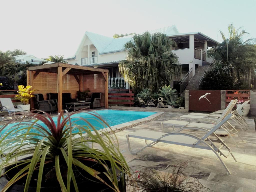 un patio trasero con piscina y una casa en LE COLONIAL, T4 à 5 mn Aeroport dans villa de standing en Sainte-Marie