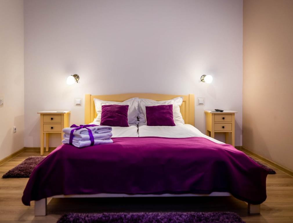 - une chambre avec un lit doté de draps et d'oreillers violets dans l'établissement Brassai Square, à Braşov