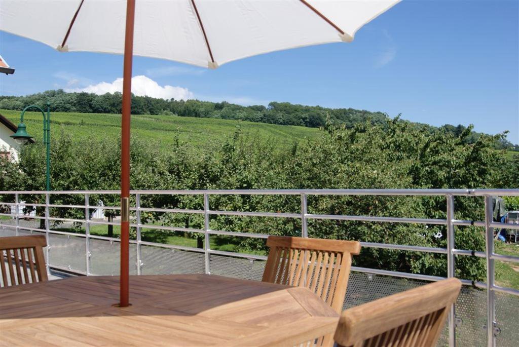 einen Holztisch mit Sonnenschirm auf dem Balkon in der Unterkunft Gîte Binnert Bader in Nothalten