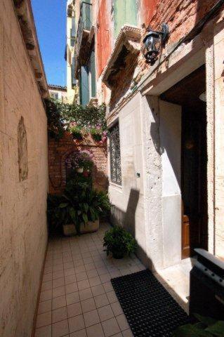 a narrow alley with a building and plants in it at Residenza Hotel San Maurizio in Venice