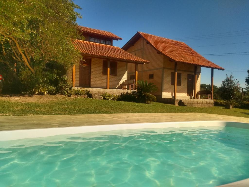 una casa con piscina frente a ella en Rosa Olas Cabanas en Praia do Rosa
