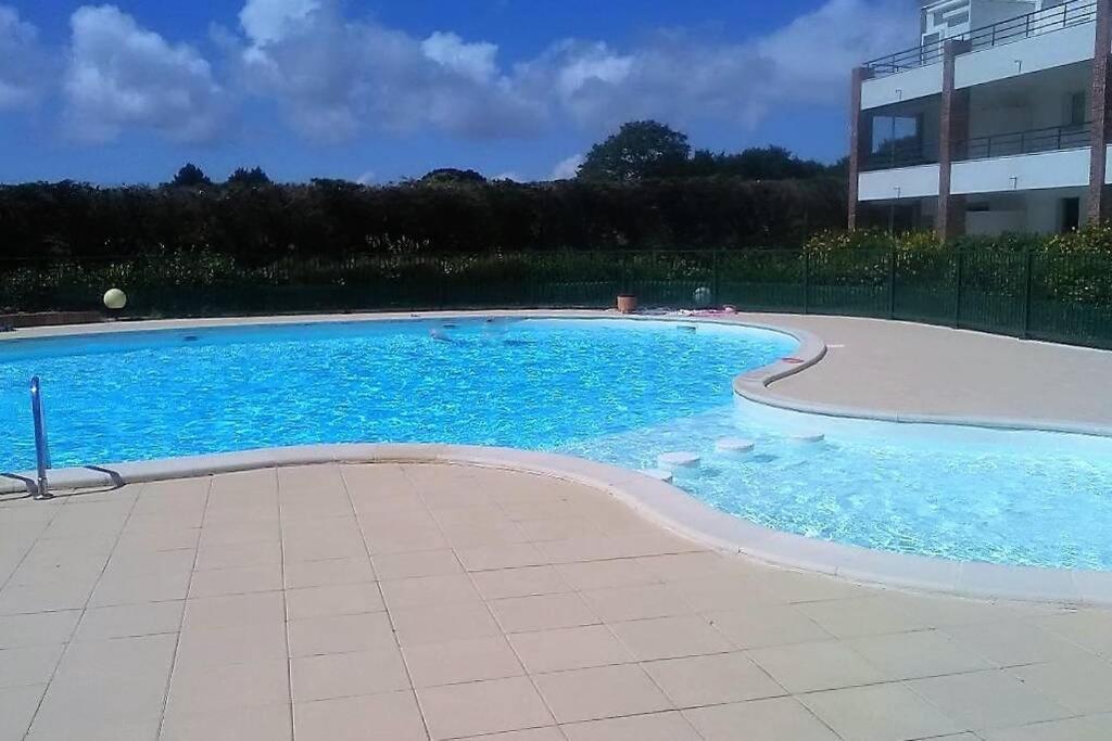 a large swimming pool with blue water in front of a building at Studio - 700m plage port - 200m golf - wifi - piscine in Pornic