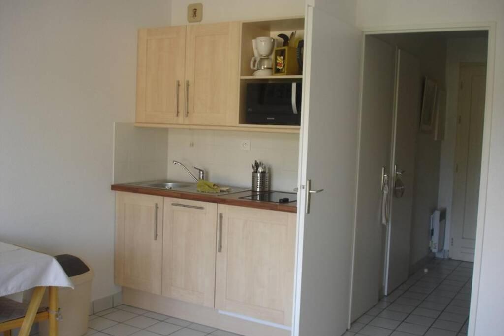 a kitchen with wooden cabinets and a sink and a microwave at Studio - 700m plage port - 200m golf - wifi - piscine in Pornic