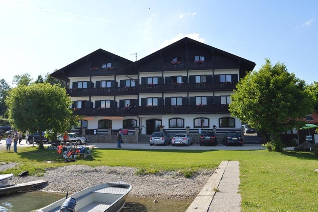 un grand bâtiment avec des voitures garées devant lui dans l'établissement Gästehaus Grünäugl am See, à Gstadt am Chiemsee