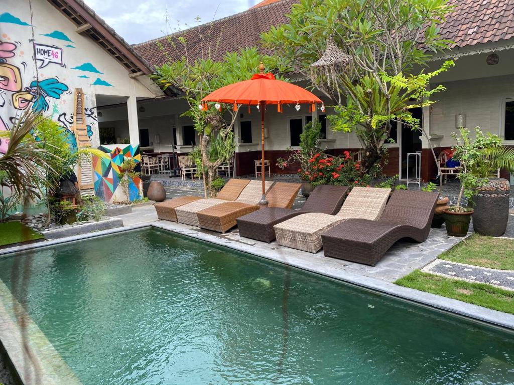 - une piscine avec des chaises et un parasol à côté d'une maison dans l'établissement Guest House Home 46 Bali, à Canggu