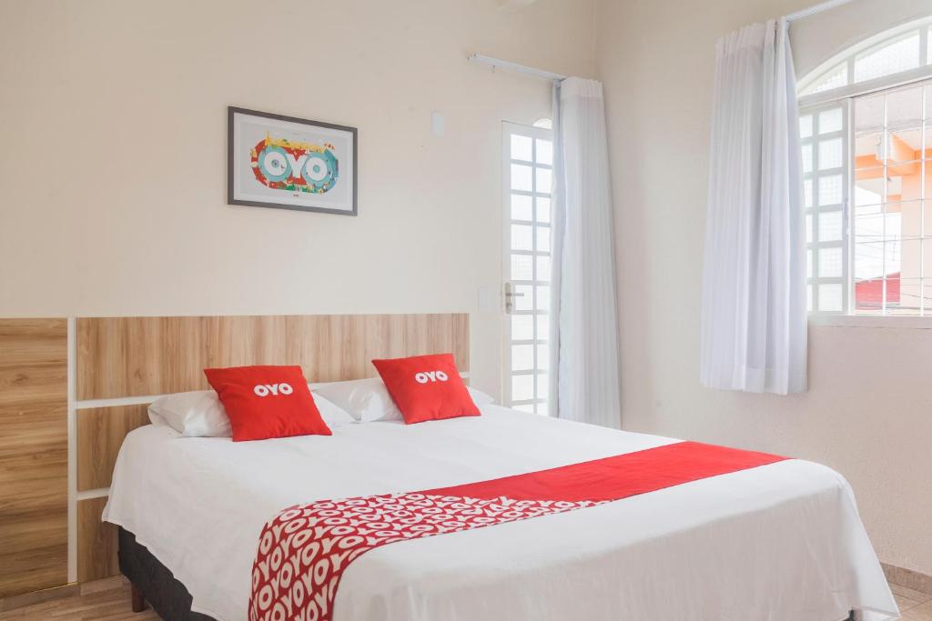 a bedroom with a large white bed with red pillows at OYO Hotel Brisa Tropical, Brasília in Brasília