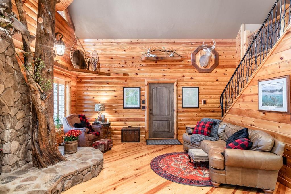 a living room in a log cabin with a staircase at Iron Mountain Lodge - Beautiful Cabin With Forest & Mountain Views! in Butler