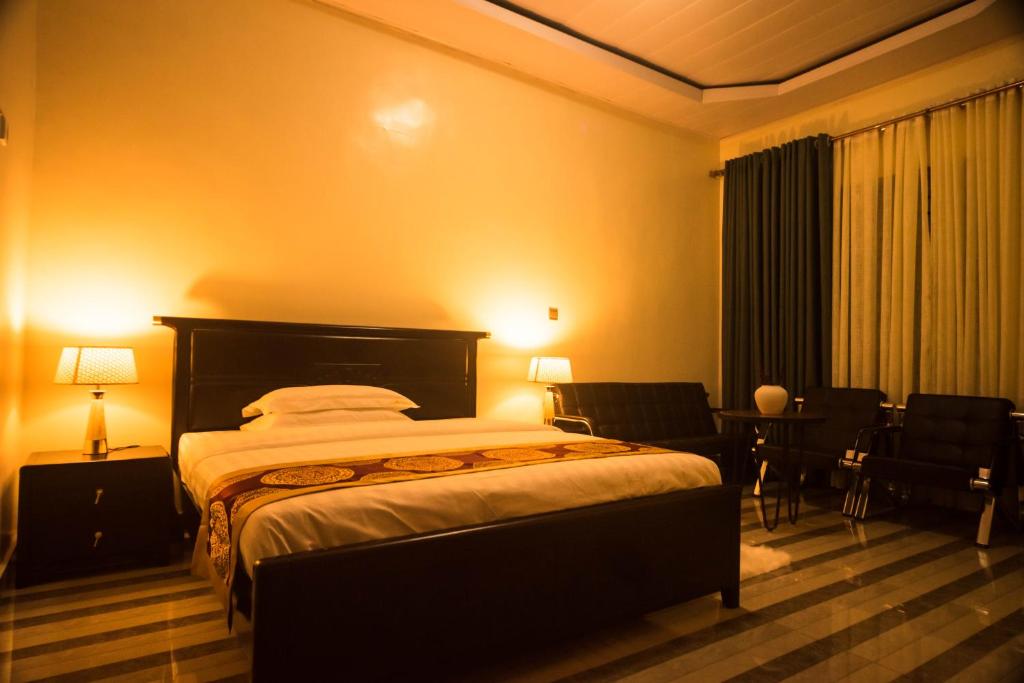 una camera con letto, tavolo e sedie di AVISHA TOWN HOTEL a Kigali